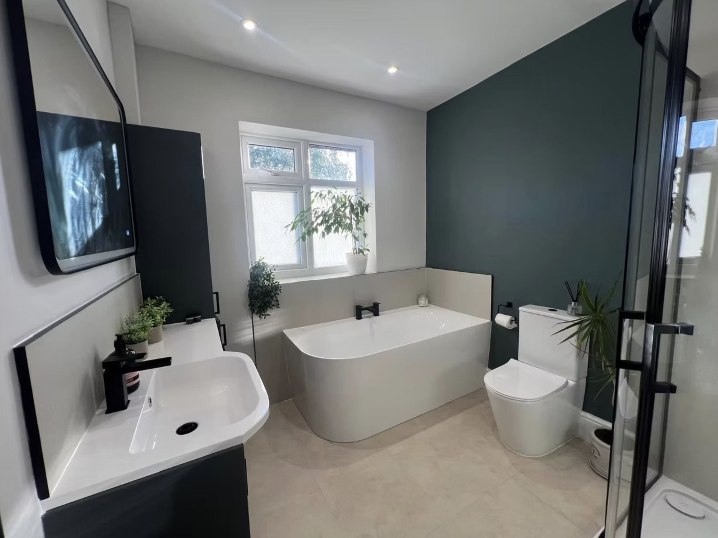 The Green Bathroom: a deep green feature wall, back-to-wall bath and matt black brassware.